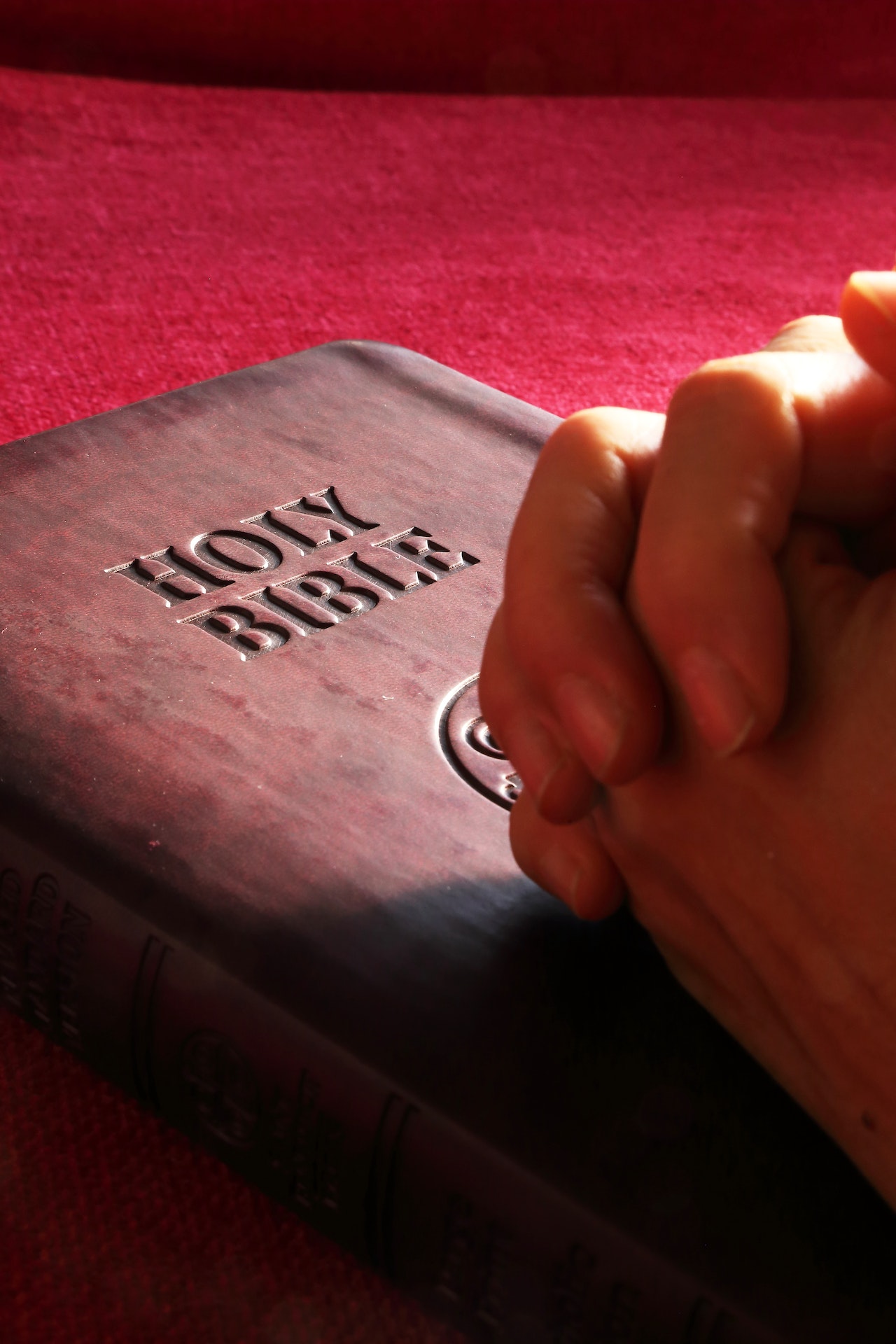 Hands praying over a bible book